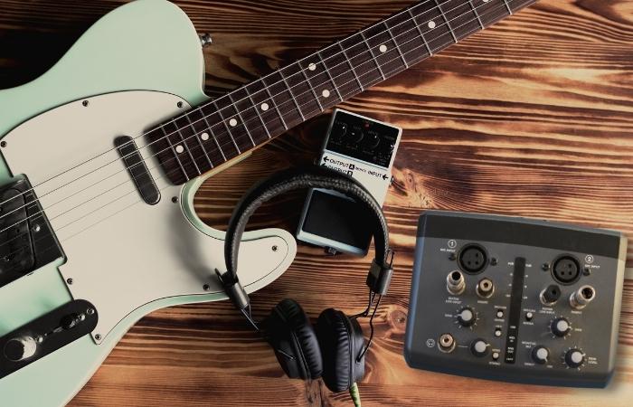 A guitar, pedal, audio interface, and headphones