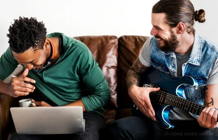Two Men Writing With A Laptop And Guitar