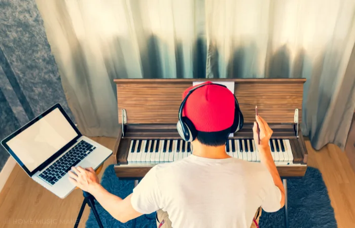 Man Writing Music With A Piano And A Laptop 1